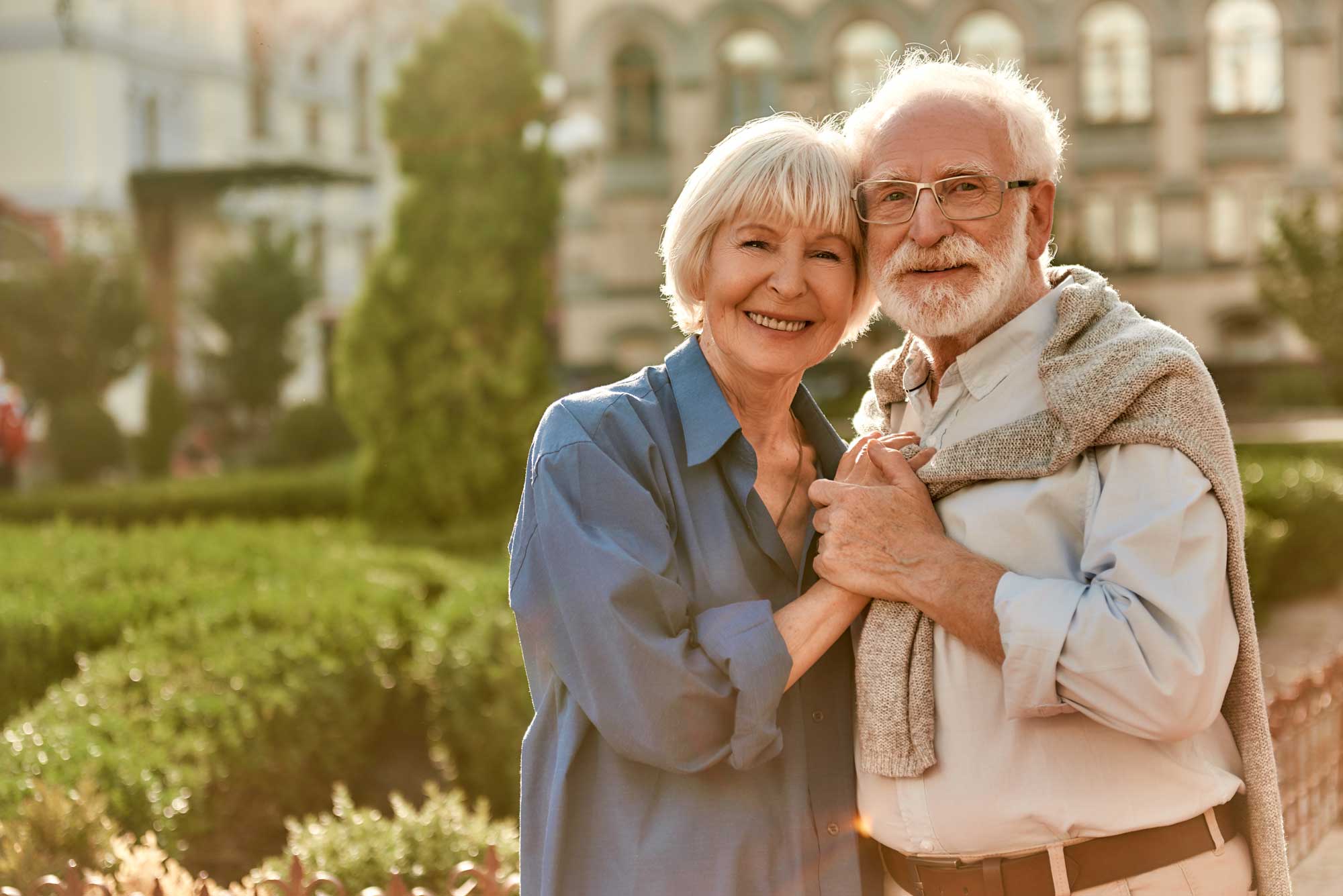 Portrait of cheerful happy senior couple bonding to each other and holding hands while standing in the park together